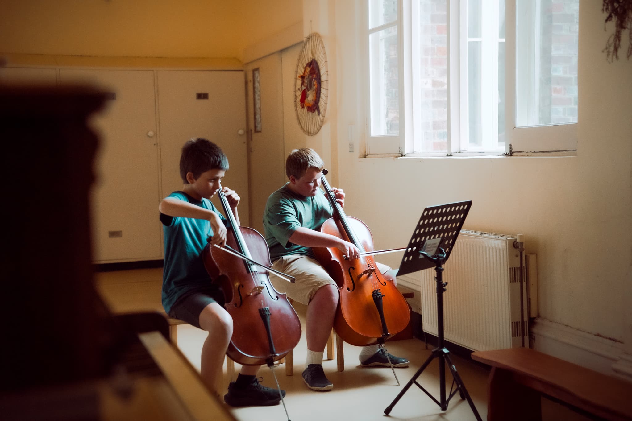 Two students playing cellos together as a duet