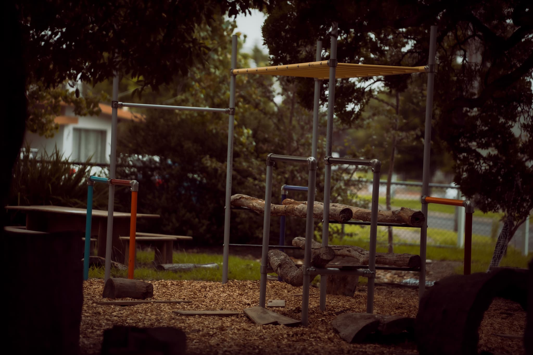 Natural playground with climbing frames under mature trees